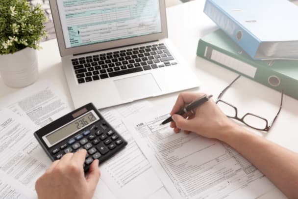 Formularios de impuestos y una calculadora sobre un escritorio